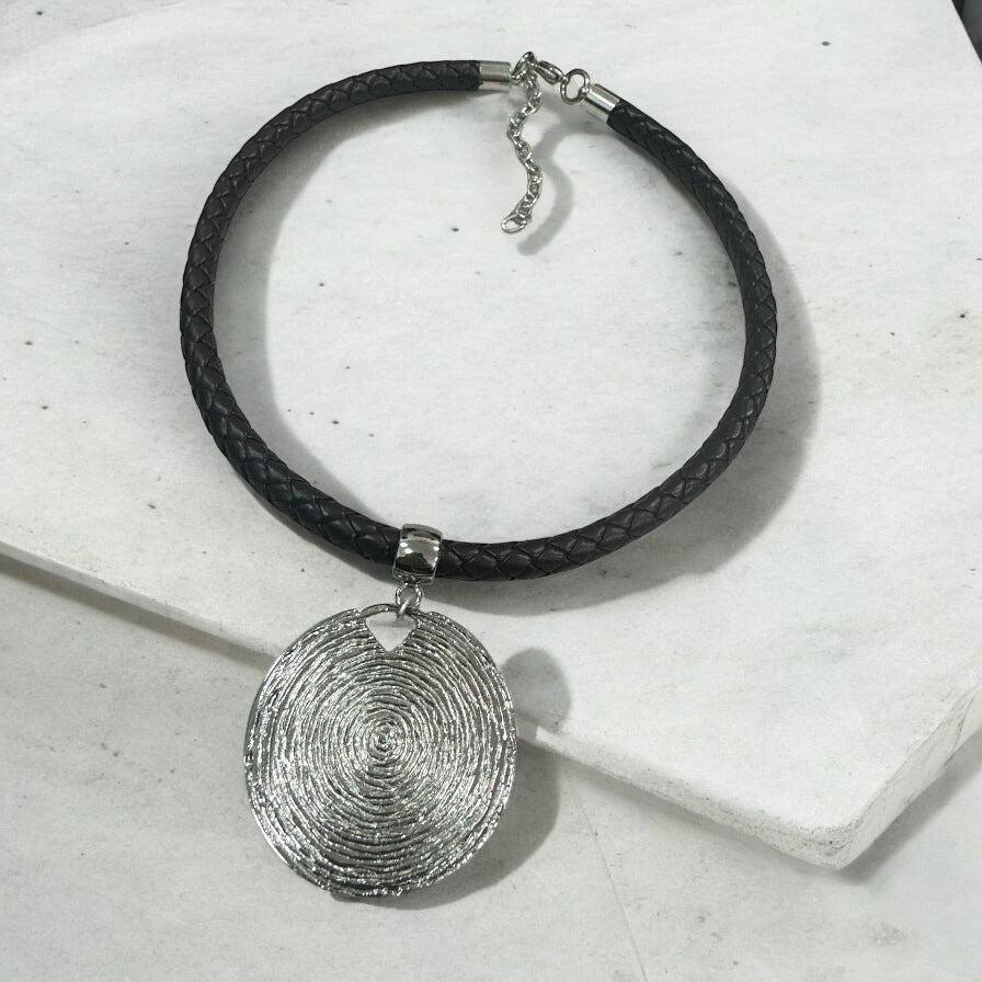 Colar preto trançado com pingente prateado oval e fecho metálico