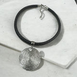 Colar preto trançado com pingente prateado oval e fecho metálico