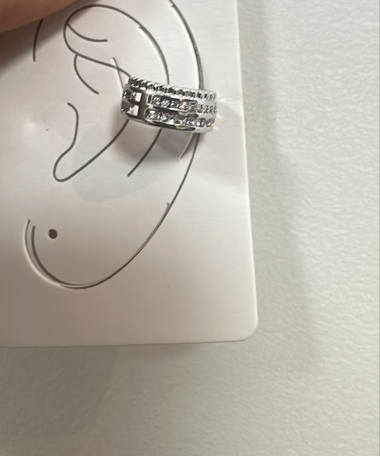 Piercing auricular prateado em aro com fileira de pedras brilhantes