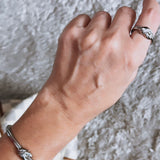 Pulseira prateada com pingentes de nozinho no pulso