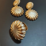 Anel dourado largo com detalhes radiais em formato de flor