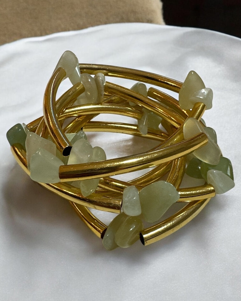 Pulseira dourada com pedras verdes claras translúcidas e hastes trançadas