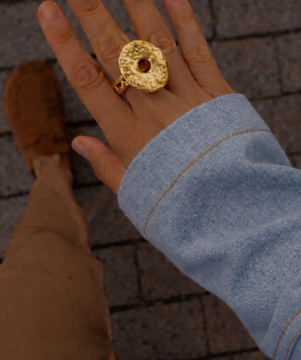 Anel dourado oval texturizado com pedra central clara