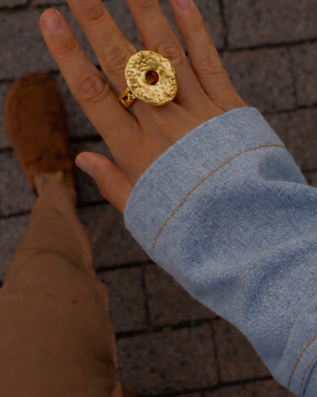Anel dourado oval texturizado com pedra central clara