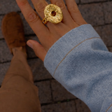 Anel dourado oval texturizado com pedra central clara