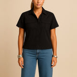 Blusa preta com gola polo, frente aberta por botões e mangas curtas, com bolsos