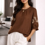 Blusa marrom com bordado claro nas mangas bufantes e gola franzida