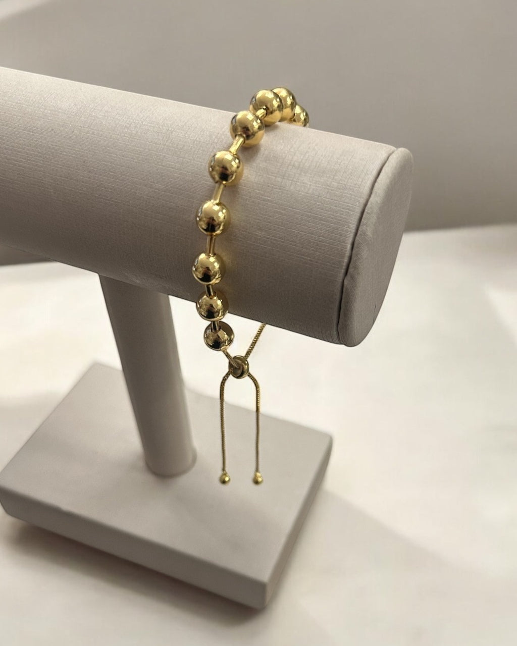 Pulseira Lia dourada com contas esféricas e pingente pendente de elos.