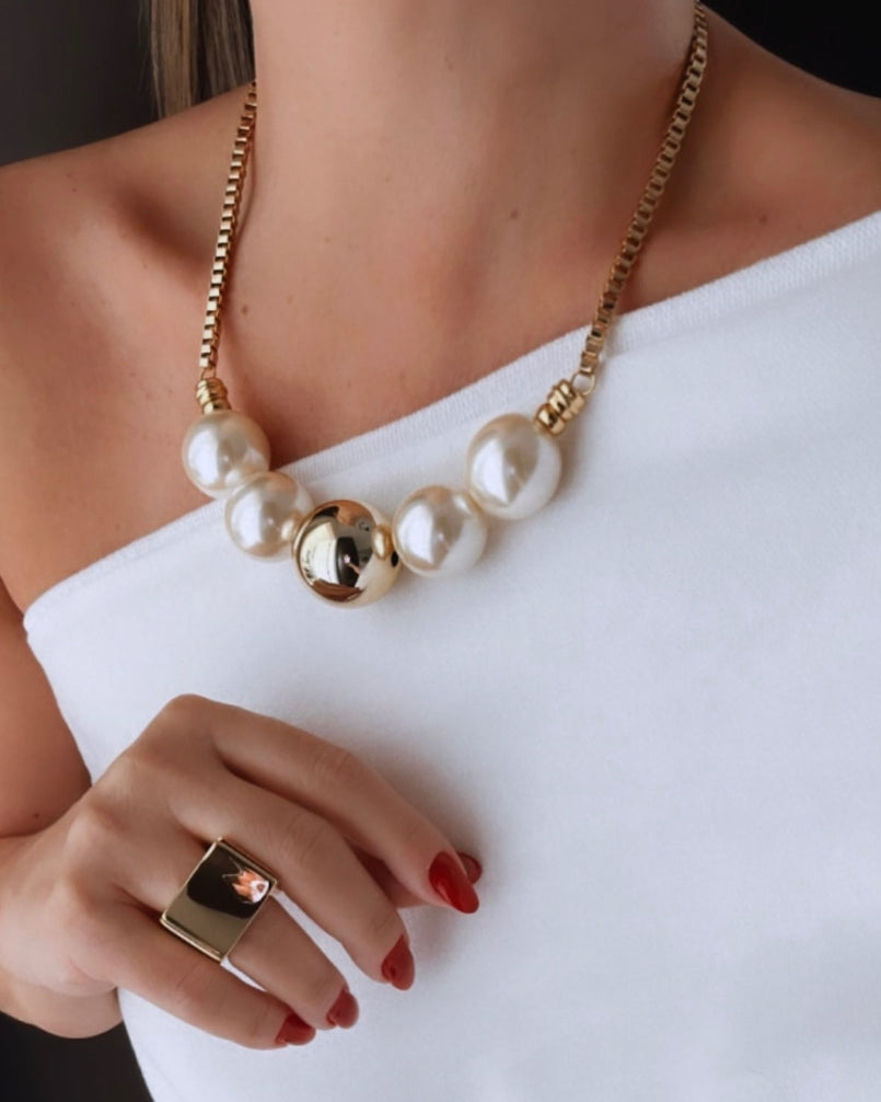 Anel dourado com pedra escura quadrada e detalhes em metal