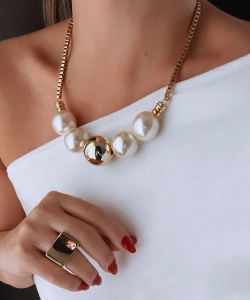 Anel dourado com pedra escura quadrada e detalhes em metal