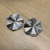 Par de brincos prateados em formato circular com textura radial