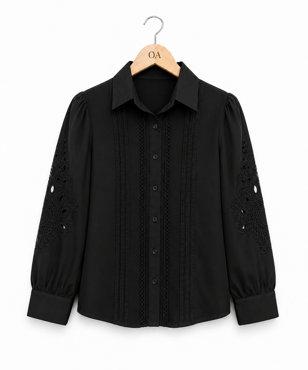 Camisa preta com botões e bordado central; detalhes vazados nos punhos e mangas