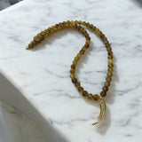 Colar de contas dourado com pingente de chifre e fecho metálico