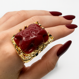 Anel Ursula com pedra vermelha escura em aro dourado com borda trabalhada