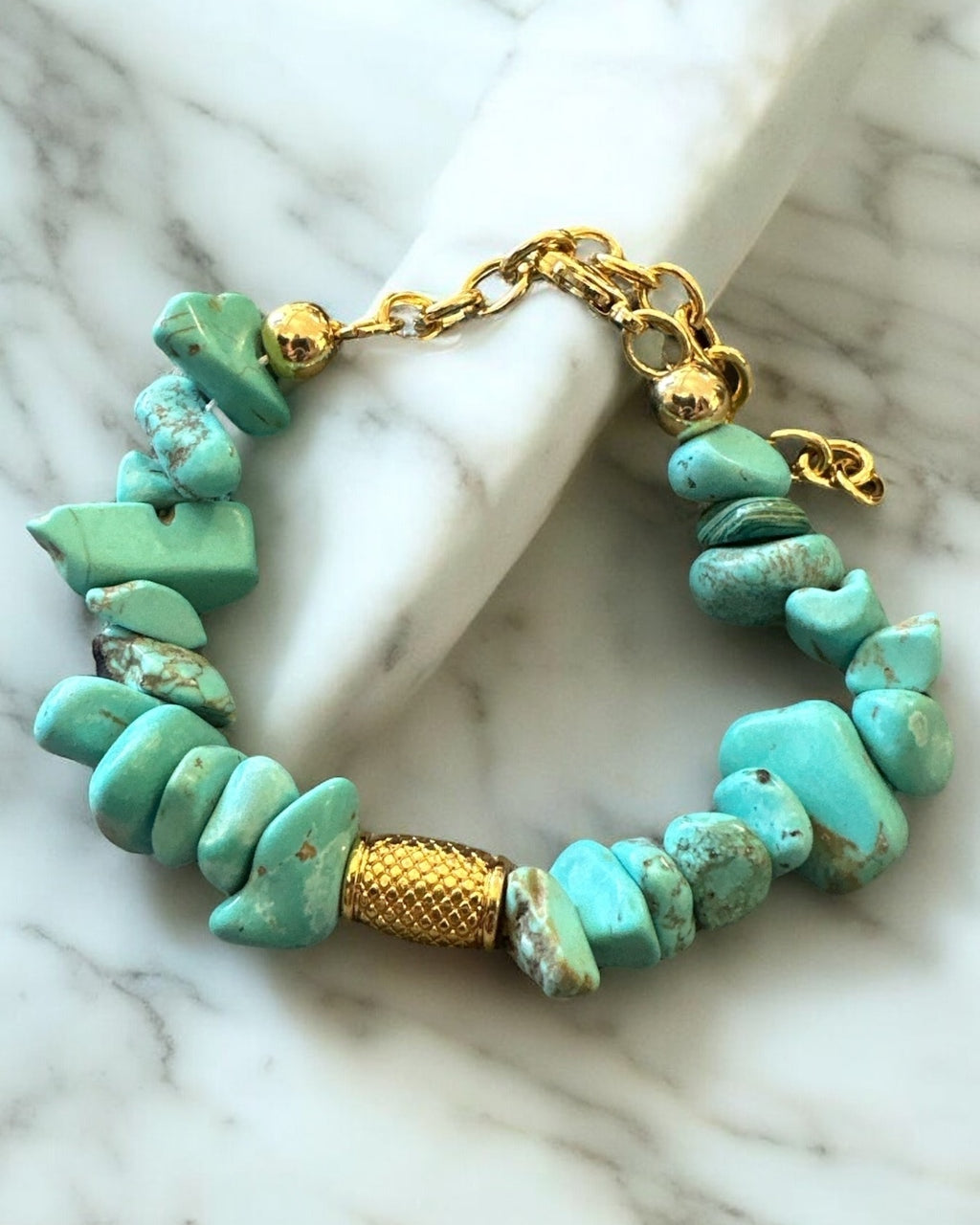 Pulseira com contas de pedra azul-turquesa e fecho dourado em corrente.