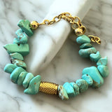Pulseira com contas de pedra azul-turquesa e fecho dourado em corrente.