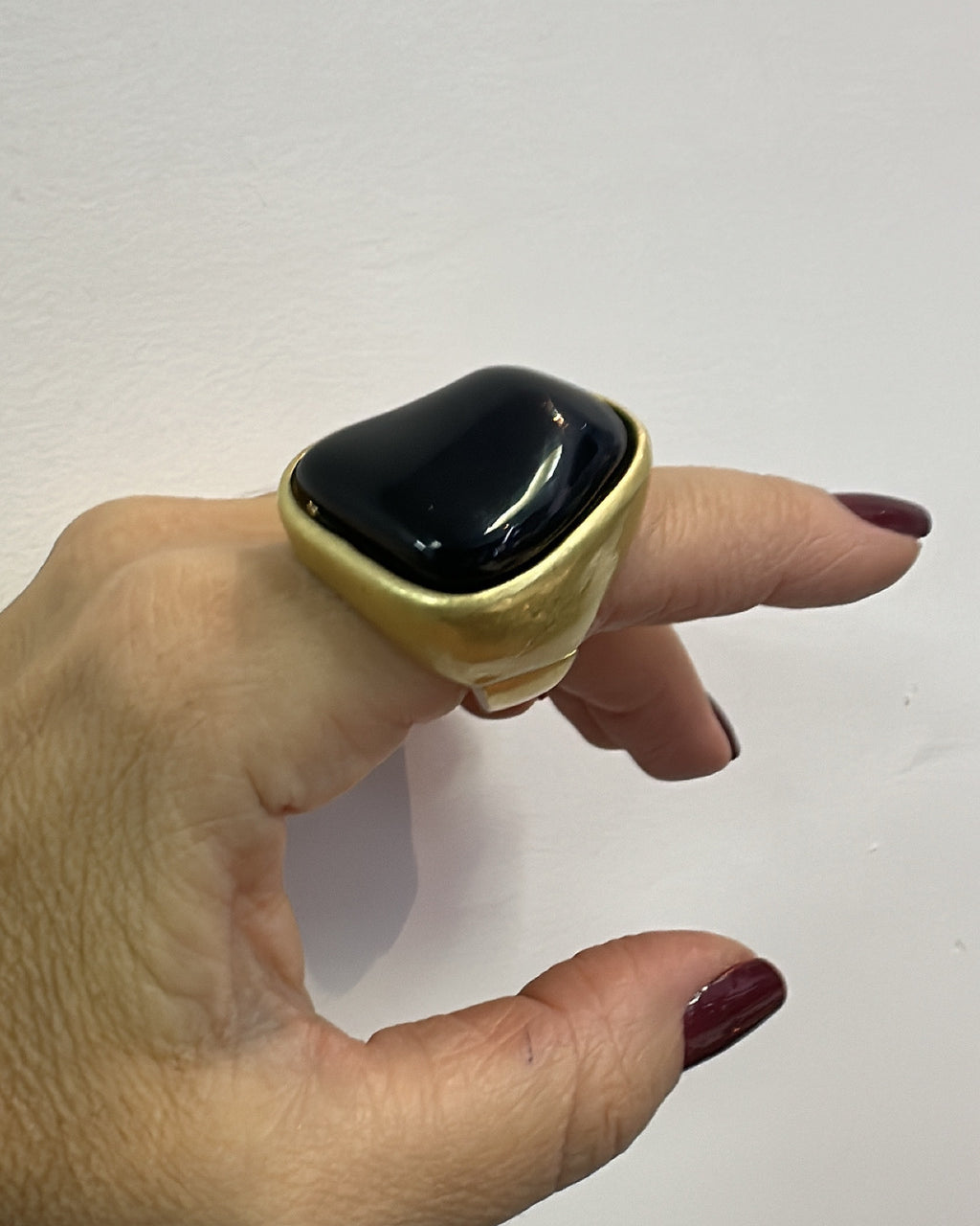 Anel com pedra oval preta em moldura dourada, design abaulado
