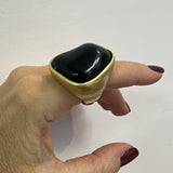 Anel com pedra oval preta em moldura dourada, design abaulado
