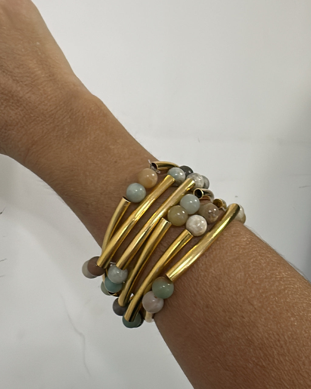 Pulseira dourada com várias voltas e contas azul-claro e brancas