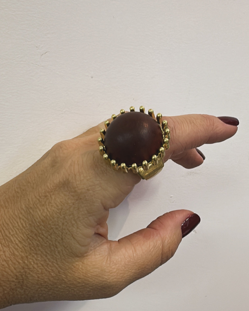 Anel Bia dourado com pedra oval escura e borda de pequenas esferas douradas