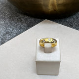 Anel dourado com pedras no topo e detalhe central retangular