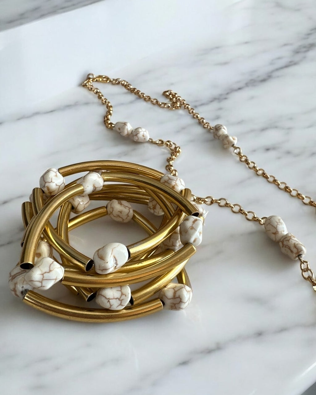 Mix de pulseiras Indra: braceletes dourados e pulseira de corrente com contas brancas