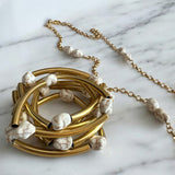 Mix de pulseiras Indra: braceletes dourados e pulseira de corrente com contas brancas