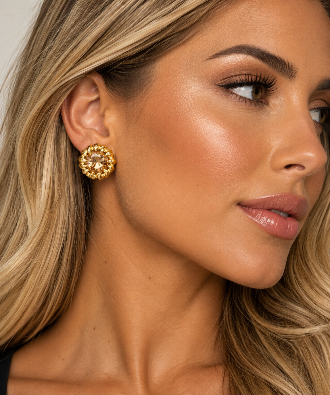 Brinco Alba dourado com pedra central facetada em tom champagne, usado na orelha.