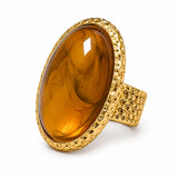 Anel Yara com resina citrina oval âmbar, acabamento dourado e borda trabalhada