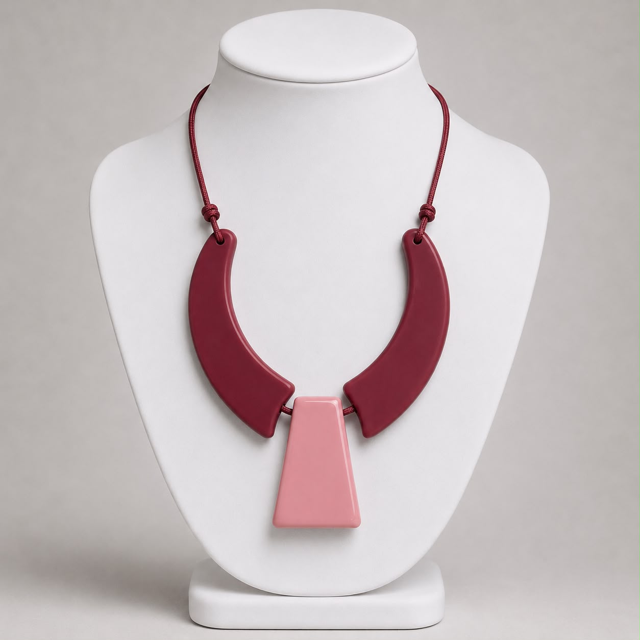 Colar de resina com peças curvas vinho e pingente central rosa.