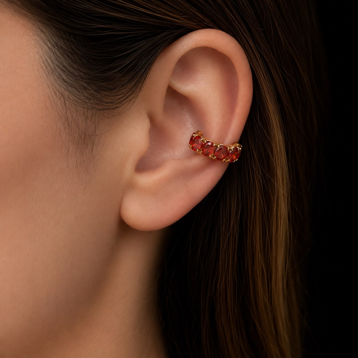 Piercing na orelha com argola dourada e pedras vermelhas