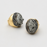 Par de anéis Fira com aro dourado e pedra cinza escura oval com detalhes cravejados