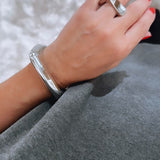 Pulseira prateada com elos retangulares no punho