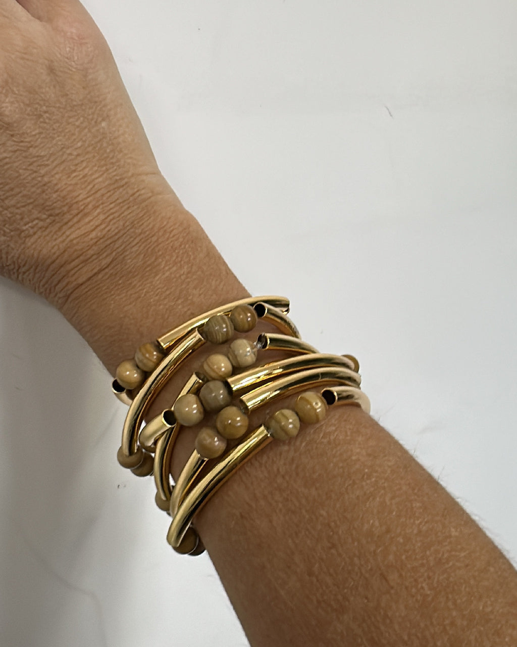 Pulseira dourada com várias voltas e contas marrom/acinzentadas