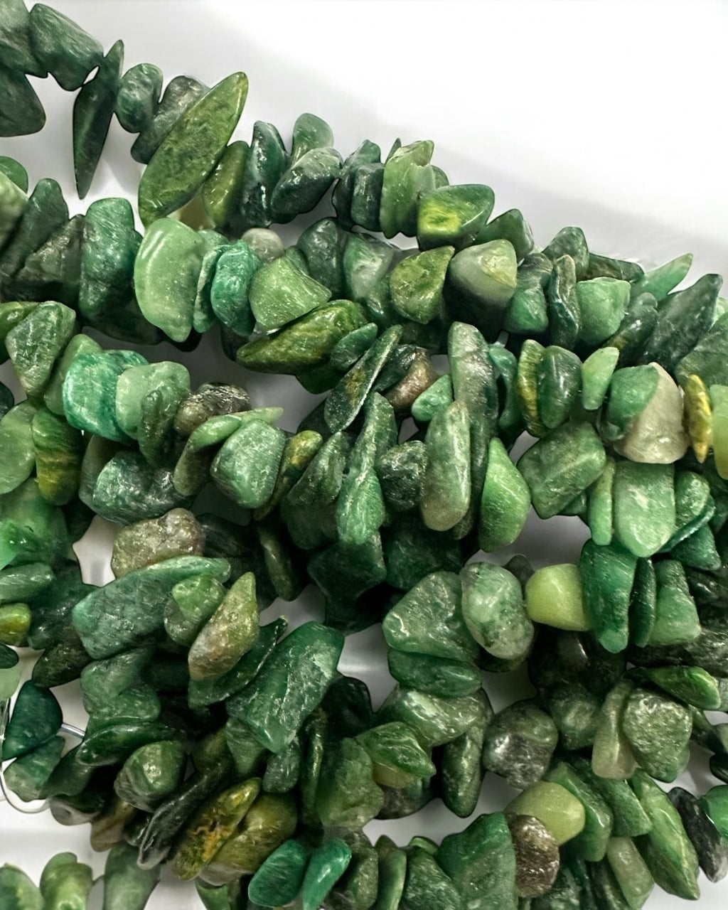 Fio de pedras verdes com lascas irregulares e algumas peças esverdeadas escuras