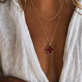 Colar dourado com pingente trevo vermelho
