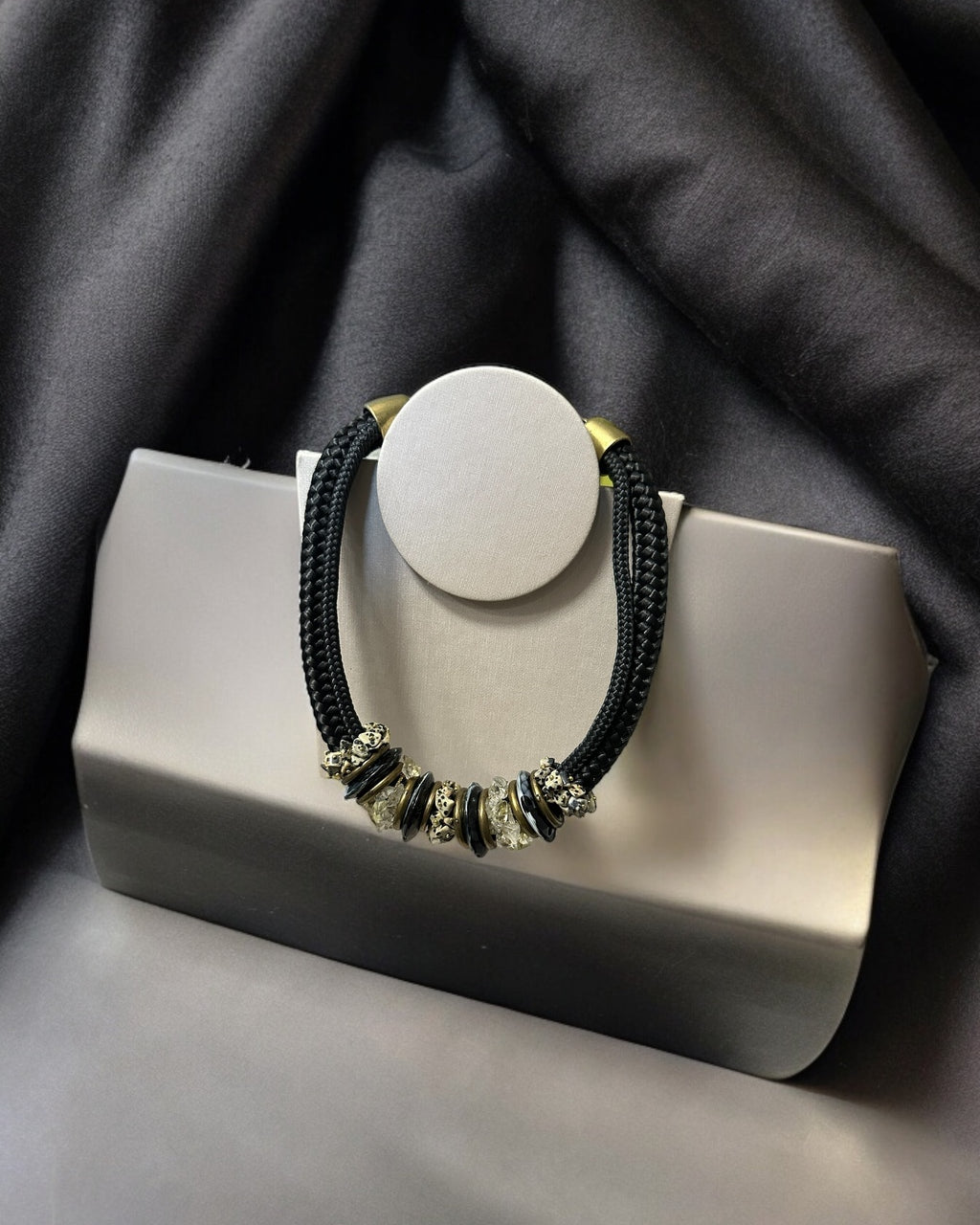 Colar Inês com pingente circular branco, cordão preto trançado e metal dourado frontal