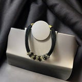 Colar Inês com pingente circular branco, cordão preto trançado e metal dourado frontal
