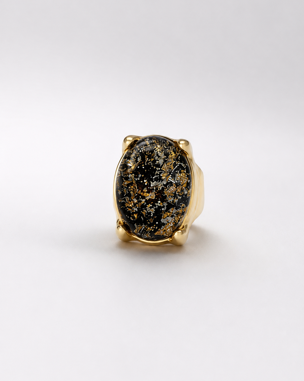 Anel oval com pedra escura salpicada de dourado em aro dourado