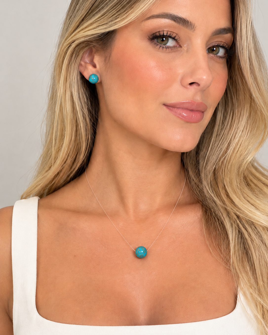 Conjunto de colar e brinco com pequenas pedras turquesa, usado no pescoço e na orelha.