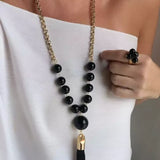 Colar Louise com correntes douradas, contas pretas e pingente com franja