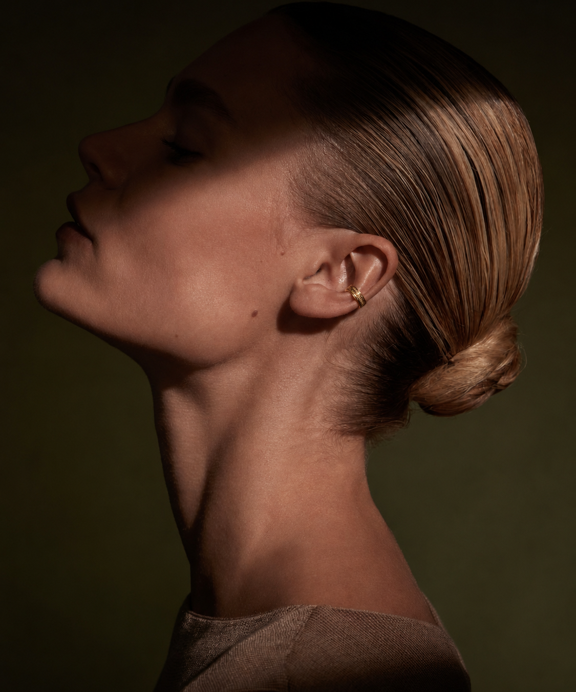 Ear cuff dourado com pedras brilhantes no lóbulo da orelha