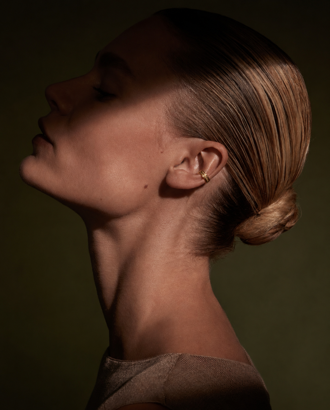 Ear cuff dourado com pedras brilhantes no lóbulo da orelha