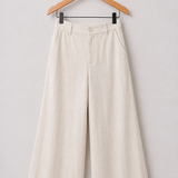 Calça pantalona creme clara, cintura com passantes e pregas, botão frontal