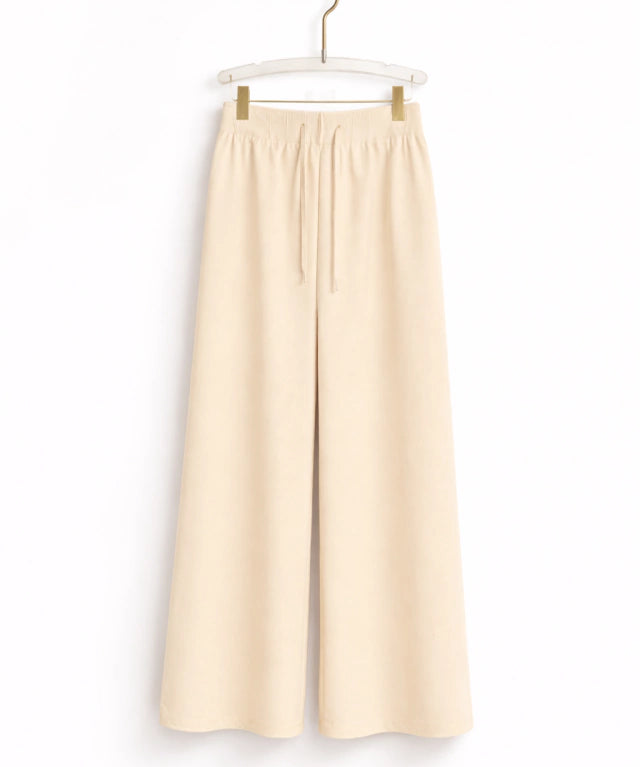 Calça de tecido creme, cintura elástica com cordão e pernas largas