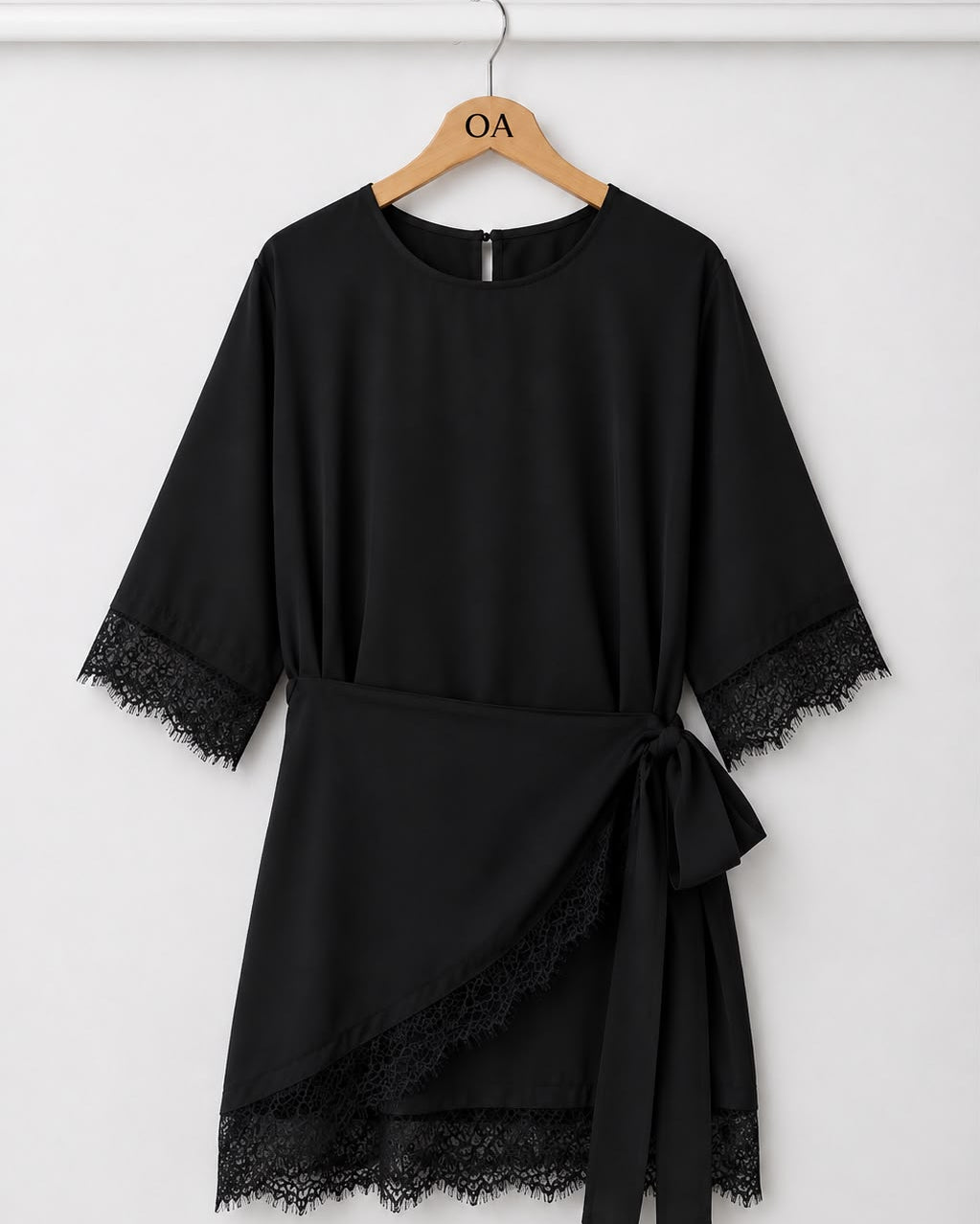 Vestido preto liso com renda nas mangas e barra, faixa frontal amarrada, sobreposição