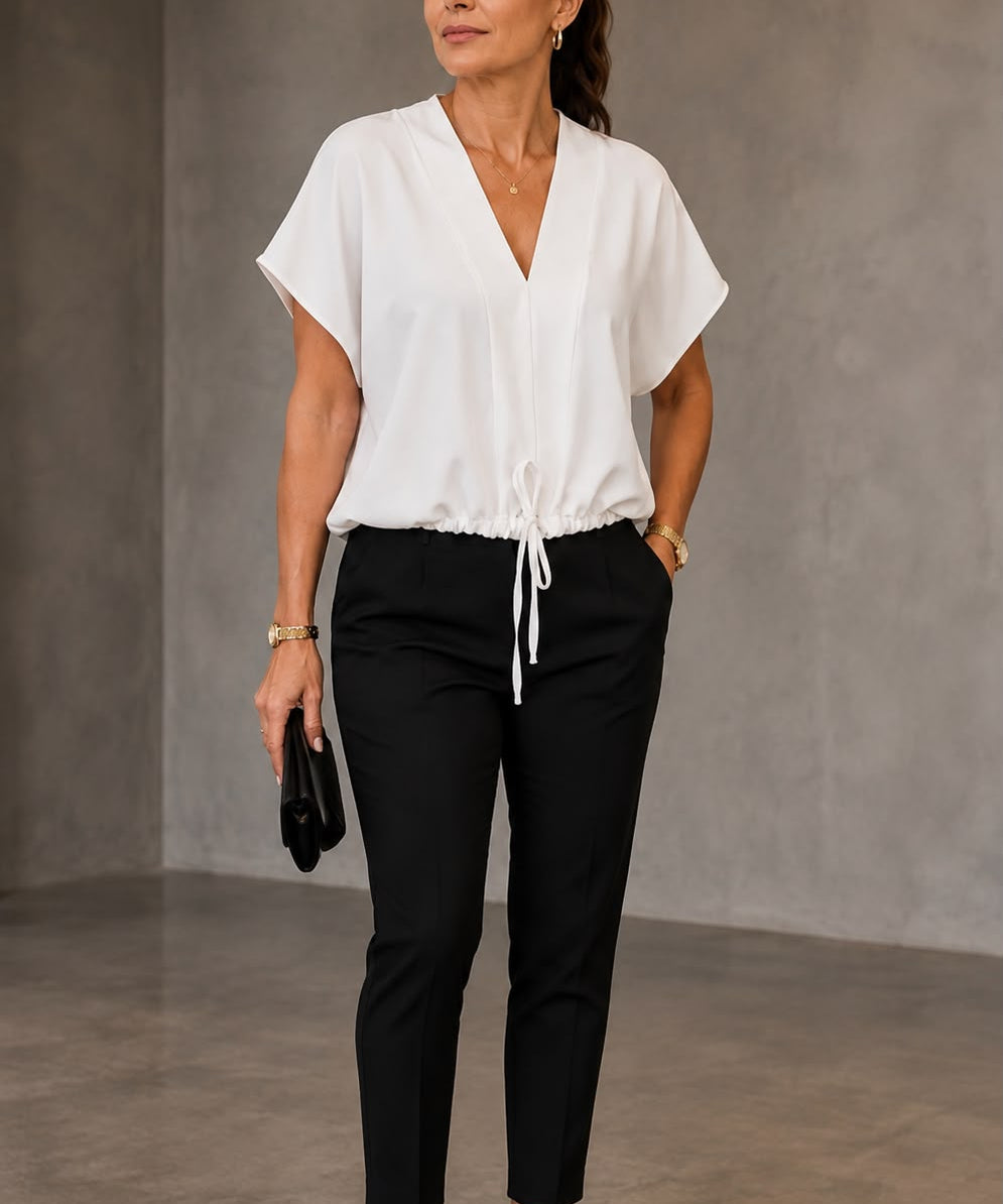 Blusa branca de decote V com amarração na barra, usada com calça preta