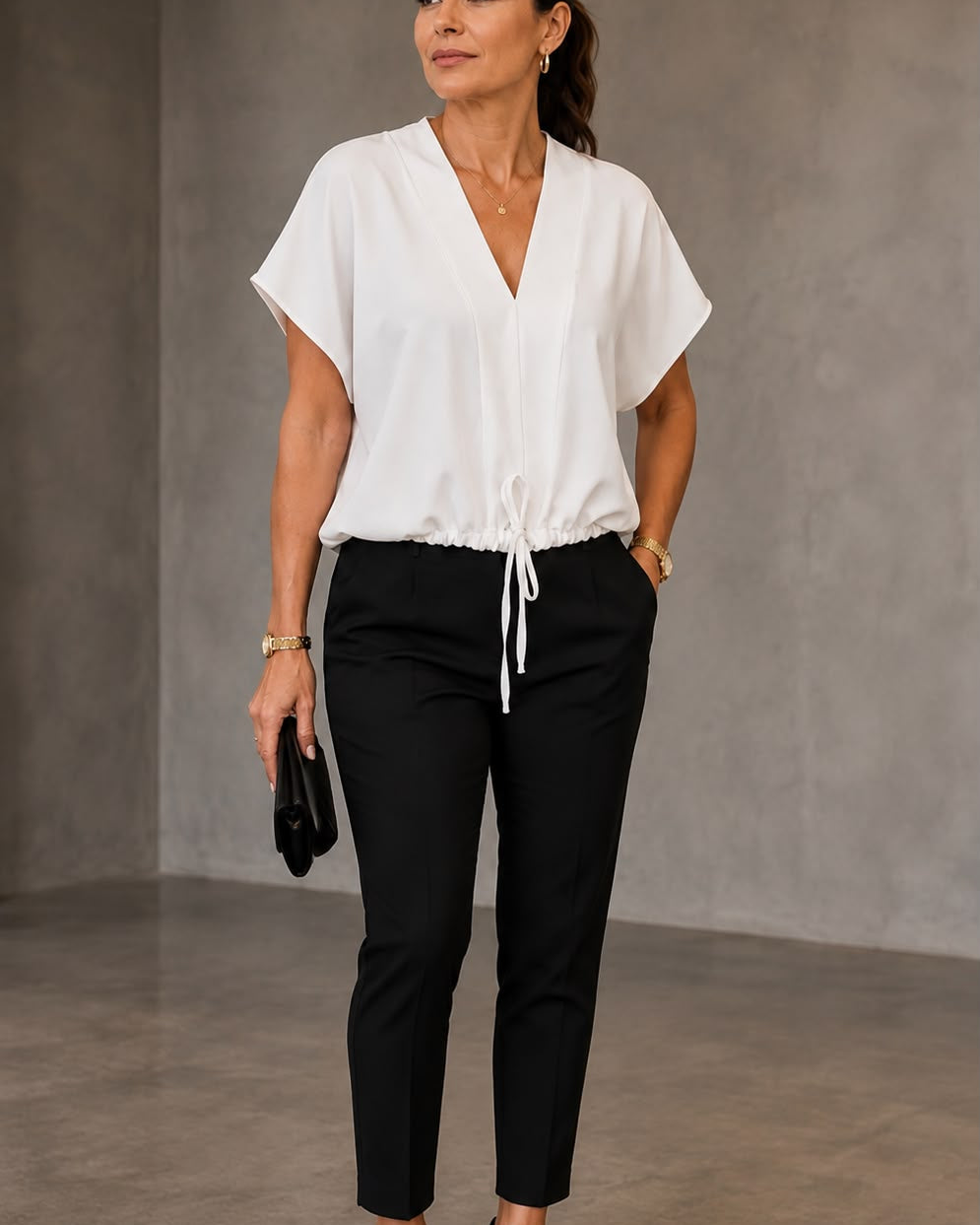 Blusa branca de decote V com amarração na barra, usada com calça preta