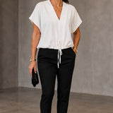 Blusa branca de decote V com amarração na barra, usada com calça preta