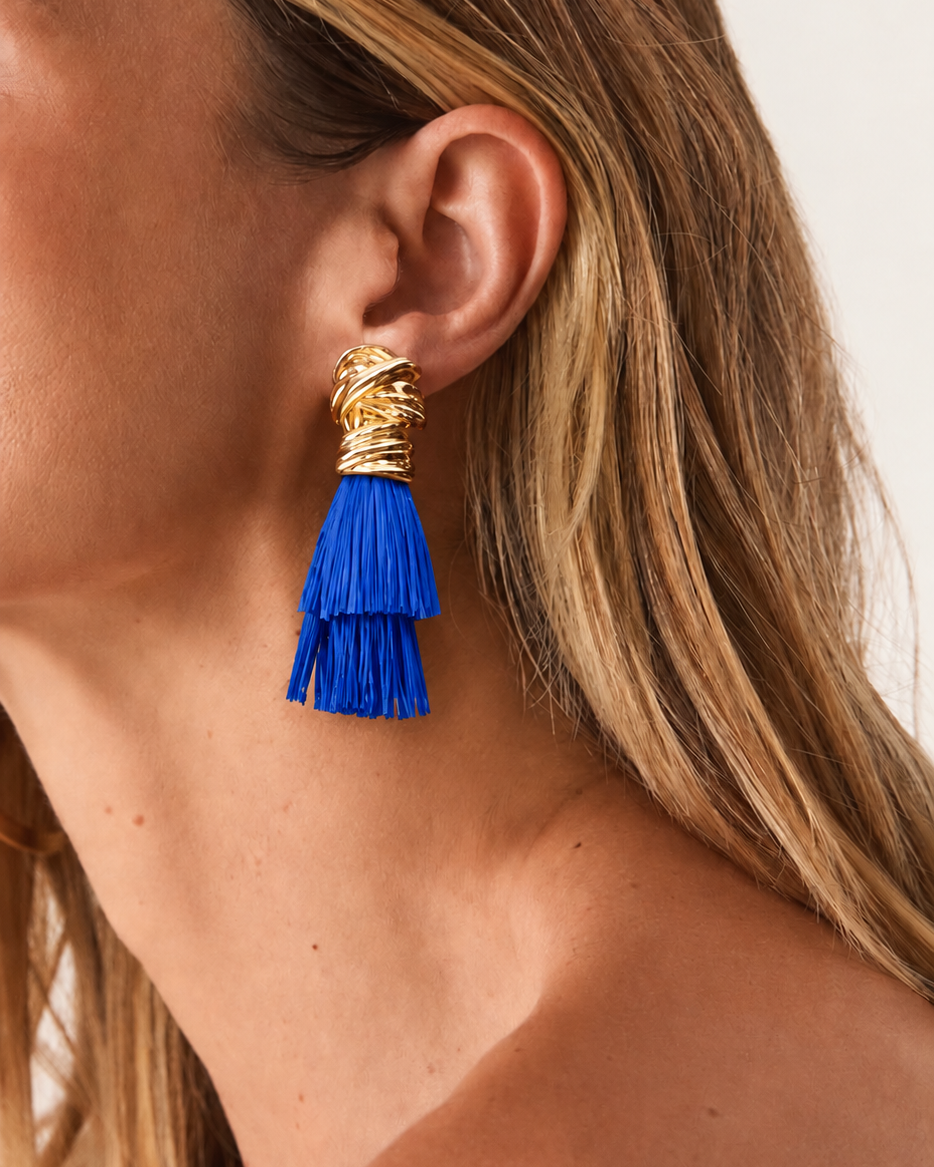 Brinco dourado com franjas azuis em camadas, detalhe na orelha